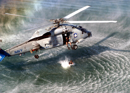 A Search and Rescue (SAR) swimmer prepares to jump from an SH-60 photo