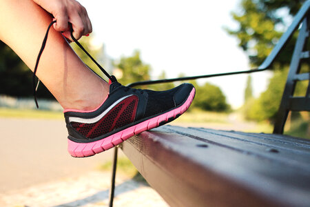 Women’s leg with sports shoes on a park bench photo