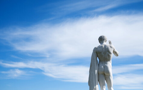 Ancient Statue of a Young Man from the Back against Blue Sky photo