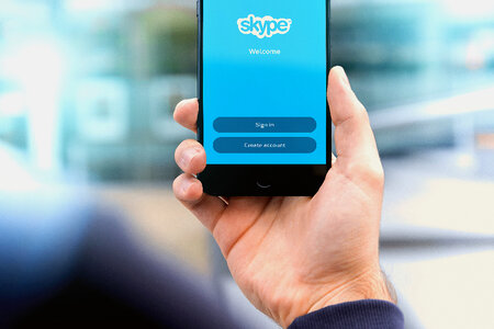 Man holding smartphone with Skype app photo