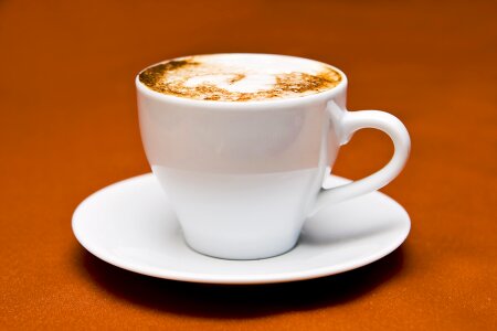 Cappuccino in a white cup on a white plate photo