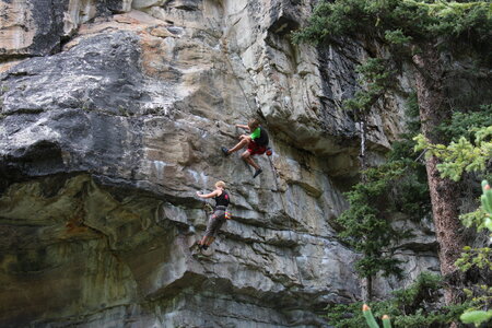 Young man climbs on a rocky wall in a valley with mountains photo