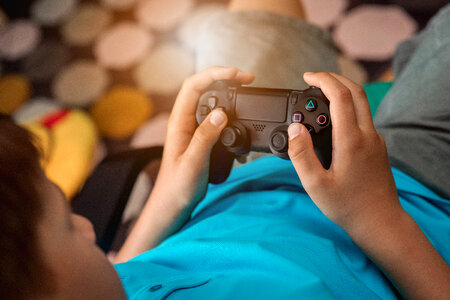 Young boy plays video games at home. Boy holds his gamepad. photo