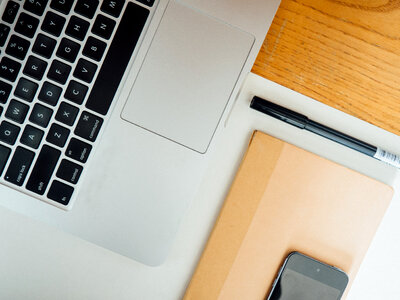 Desk with Laptop, Book, Phone, and Pen photo