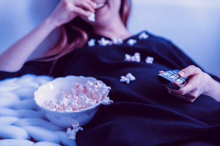 Happy woman watching TV and eats popcorn at night photo