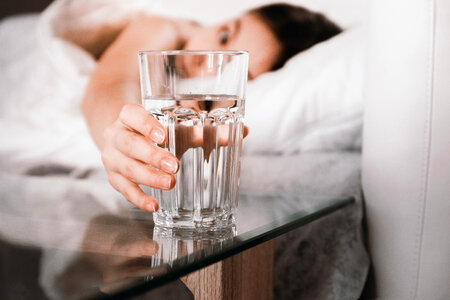 1 Close up Woman holding glass of water on bed in the morning photo