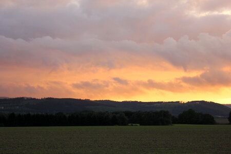 Burning sky over green fields photo