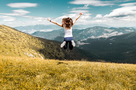 Young woman jumping on top of the summer mountains photo