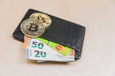 Leather wallet with money and Bitcoin on wooden background photo