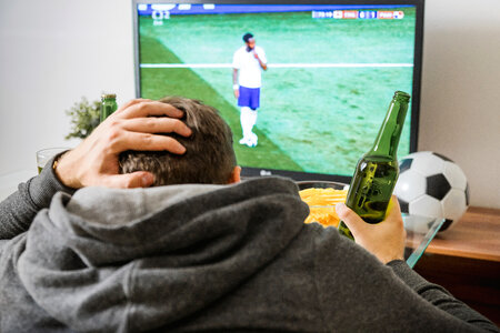 Young man watching football sport on tv at home. photo