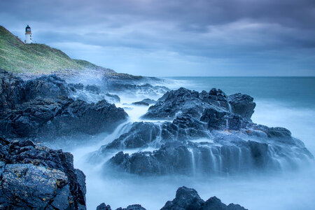 Lighthouse, rocks, waves, and ocean on a stormy day photo
