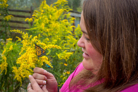 Woman holding monarch butterfly on goldenrod flower-1