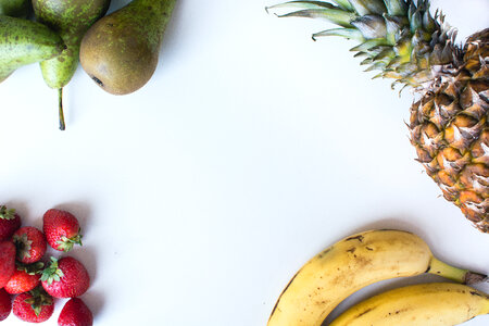 Aerial shot of fresh bananas, pears, strawberries and pineapple photo