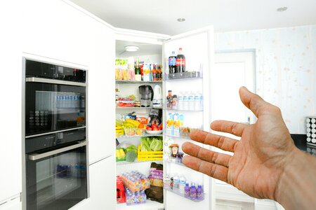 Hand Pointing to a Full Fridge