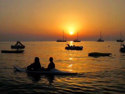 Sunset over the waters with many canoes photo