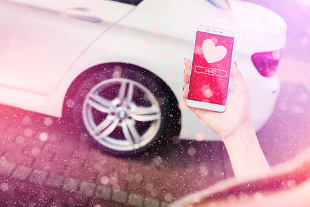 Woman’s hand holding a smartphone. On display are hearts of love. Valentine’s day concept. Sending love photo