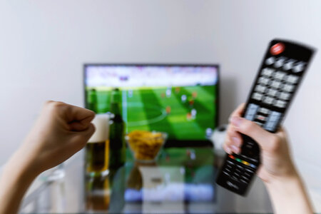 3 Watching football match on tv with remote controller. photo
