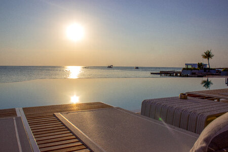 Luxury Infinity Swimming Pool and Lounge Chair at the Resort with Beautiful Sea View at Sunset photo