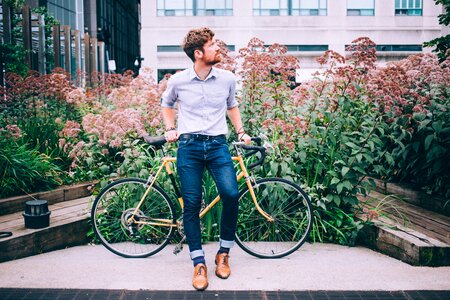 Men's Fashion Man In Shirt And Jeans Leaning On Bicycle photo