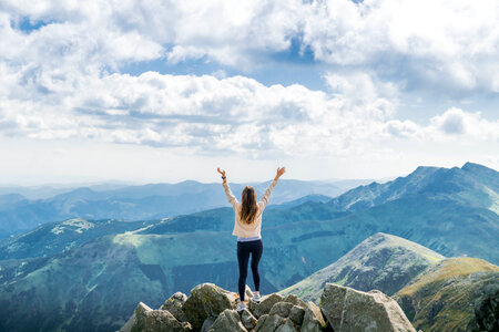 Young successful woman open arms on mountain peak photo