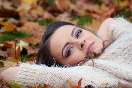 Beautiful Girl Lying in The Fall Leaves, looking at the Camera photo