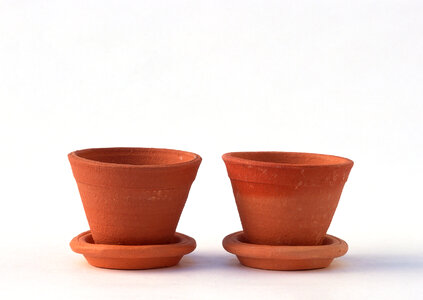 Terracotta or clay gardening pots on a wooden plank on a white photo