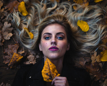 Beautifu Woman with Pink Lips Lying on Autumn Leaves photo