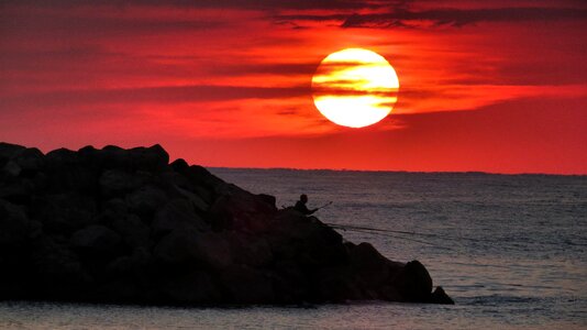 Fishermen standing on the rocks at sunrise photo