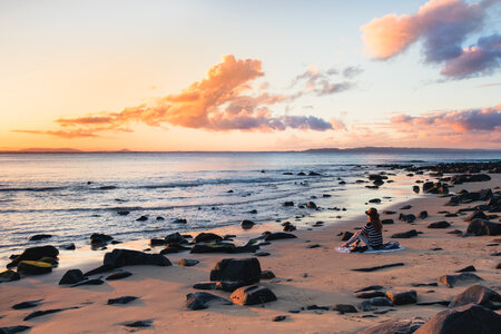 Woman in a Hat Sitting on the Beach and Admiring the Sunset photo