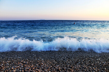 Waves crashing over pebbles on beach photo