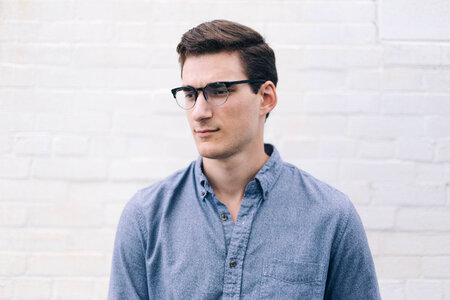Man Wearing Glasses in Front of White Brick Wall photo