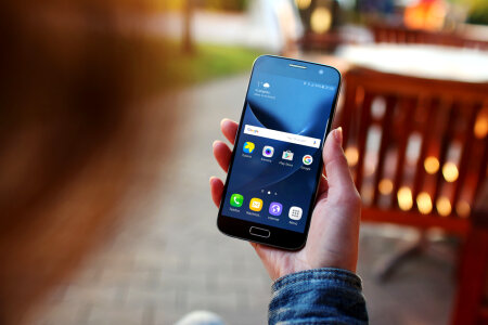 A young woman uses her smartphone Galaxy S7 outside on the pavement café photo