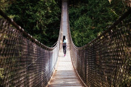 A woman walks across a suspended hiking bridge photo
