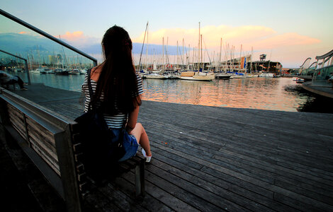Girl behind watching the sunset over the harbor photo