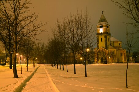 Winter park in the evening covered with snow with a row of lamps