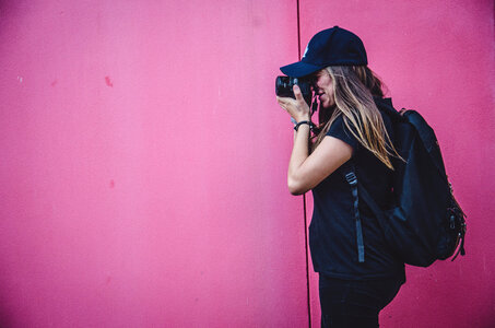 Female Photographer Shooting on a Pink Wall Background photo