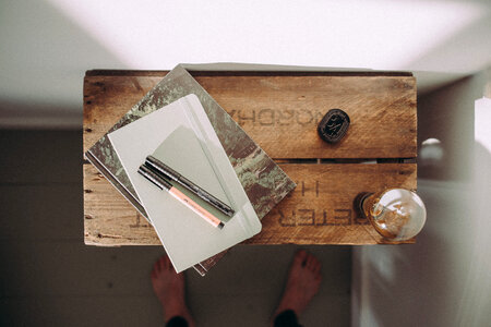 Top View of Notebook with Pen and Light Bulb on Wooden Table photo