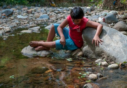 boy play with water on the river photo