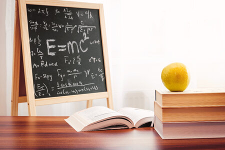 School books with apple on desk over school board background photo