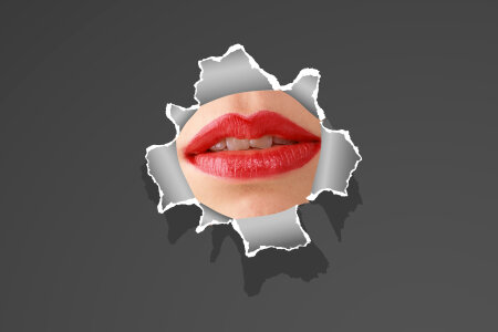 woman lip through a broken thin wall or torn paper photo