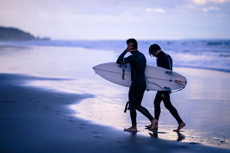 Two Men Carrying Surfing Board at the End of Day photo