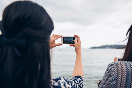 Woman Holding the White iPhone, Taking Photo of Small Island photo