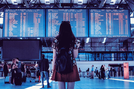 Young woman with bag checking flight timetable in international airport photo