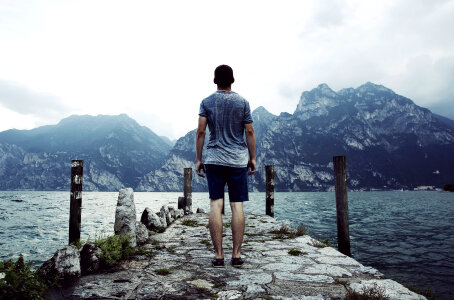 Young Man on a Stone Pier in front of a Mountain Lake photo