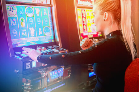 Young woman playing at slot machine in casino. She’s lucky photo
