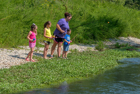 Family along steam with fishing rods