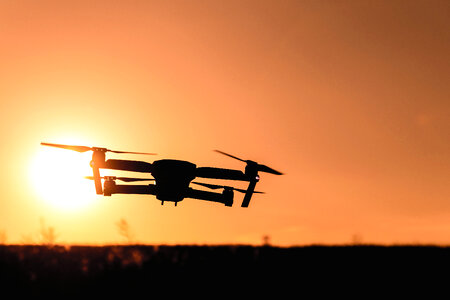 Drone silhouette with camera flying in the sunset light photo