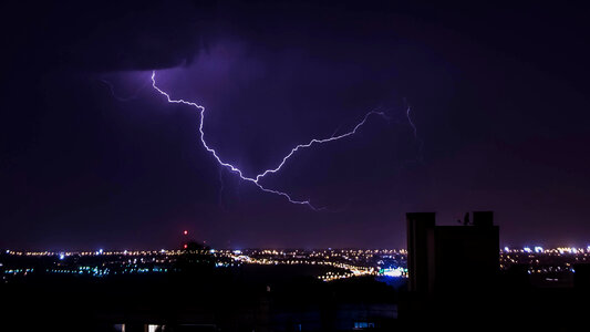 Lightning coming out of the clouds above the city photo