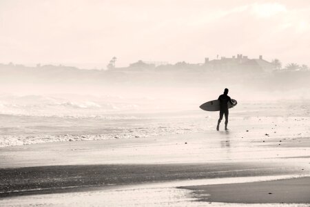 A man is walking with a surf in his hands across the sea shore photo