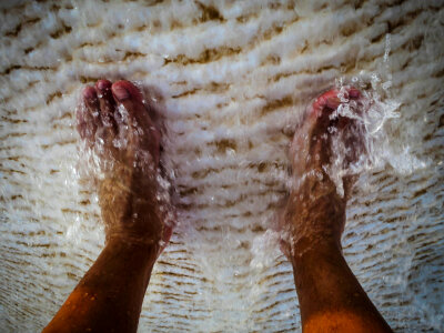 Water washes over his feet in the travertine pools. photo